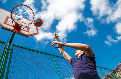 Low angle view of man playing basketball against sky
