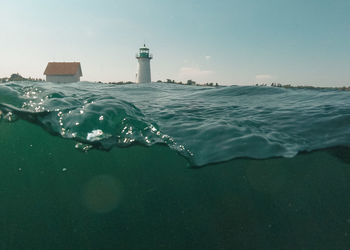 Lighthouse by sea against sky