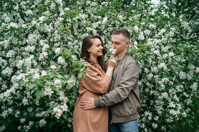 Young couple in love girl and man hugging blooming apple tree aroma of flowers outdoors