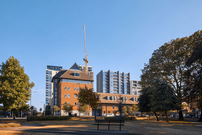 Road by buildings against clear blue sky