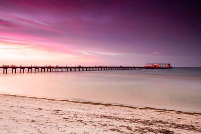 Pier over sea against sky during sunset