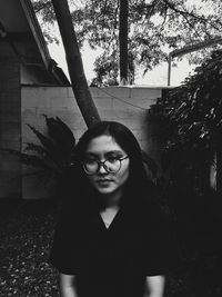 Portrait of smiling young woman standing by tree