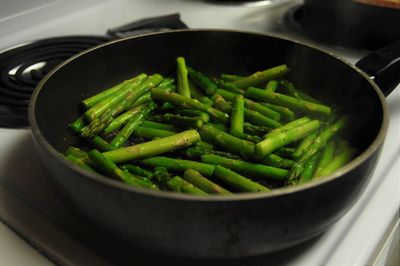 Close-up of cooking asparagus in pan on stove at home