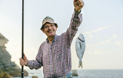 Happy senior man holding fish on fishing line