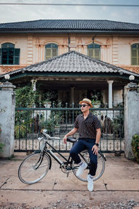 Full length of man sitting on bicycle against building