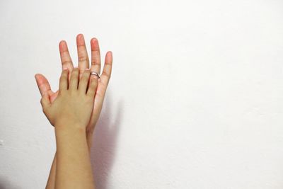 Close-up of cropped couple hands against wall