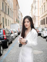 Portrait of young woman using phone while standing on street