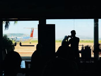 Silhouette people sitting at airplane window