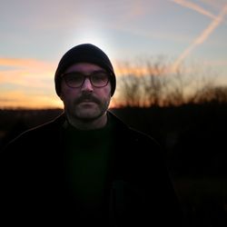 Portrait of young man standing against sky during sunset