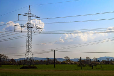 Low angle view of electricity pylon on field against sky