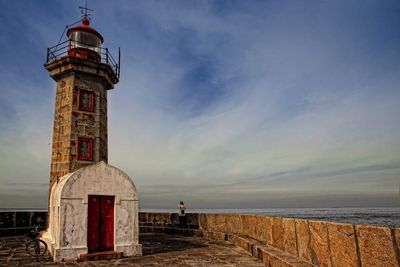 Lighthouse by sea against sky