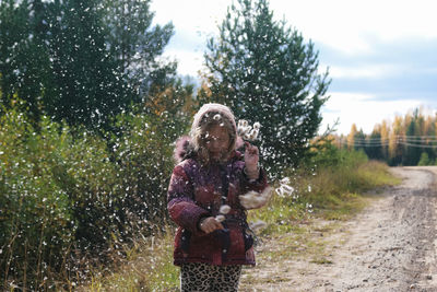 Woman standing by tree on land against sky