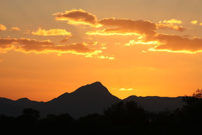 Scenic view of silhouette mountains against orange sky