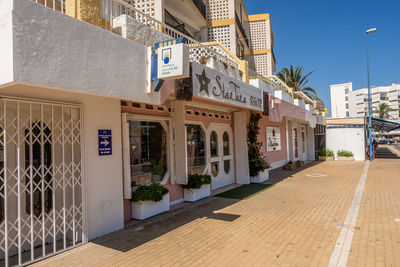 Footpath by buildings in city against sky