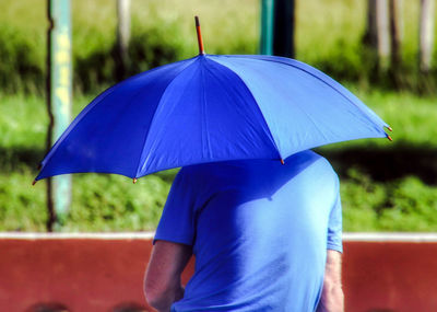 Midsection of man holding umbrella during rainy season