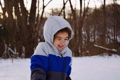 Portrait of boy standing on snow covered field