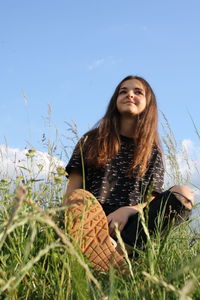 Portrait of smiling young woman against plants on field against sky