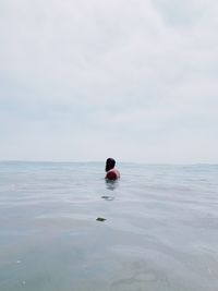 Rear view of person swimming in sea against sky