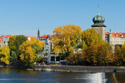 Trees by building against sky during autumn