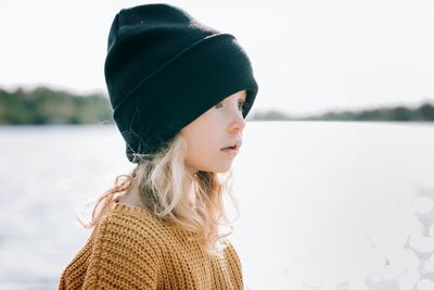 Portrait of woman looking at lake during winter