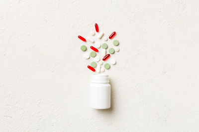 Close-up of pills spilling from bottle on table