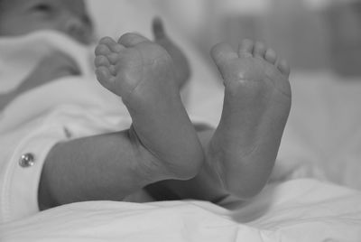 Cropped image of baby lying on bed