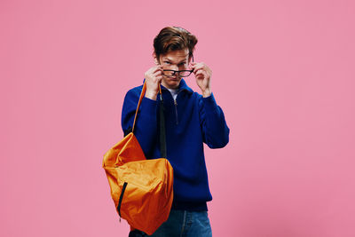 Portrait of young man standing against yellow background