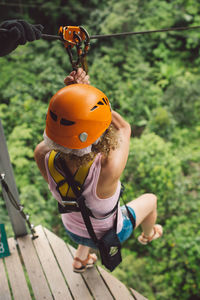 Full length of woman hanging on zip line over trees