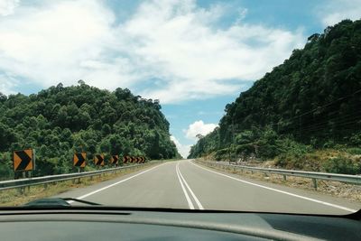 Road amidst trees seen through car windshield