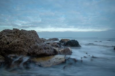 Rock formation on sea shore against sky