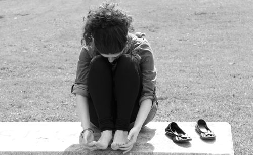 Woman touching her feet while sitting on exercise mat at park