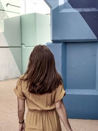 Rear view of woman standing against wall