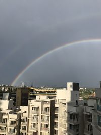 Rainbow over buildings in city against sky