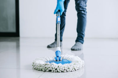 Low section of man mopping tiled floor at home