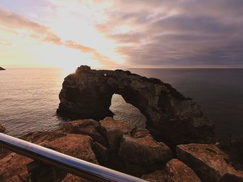Rocks on sea shore against sky during sunset