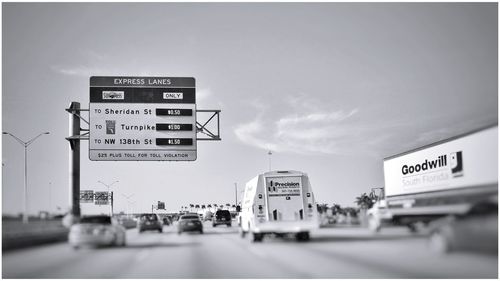 Information sign on road in city against sky