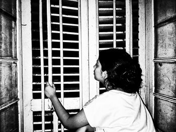 Rear view of man looking at window of building