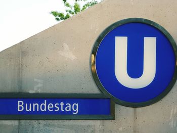 Close-up of road sign against blue wall