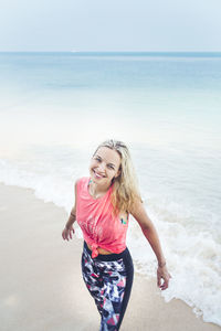 Portrait of smiling mid adult woman standing on beach