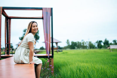 Portrait of smiling young woman sitting on field