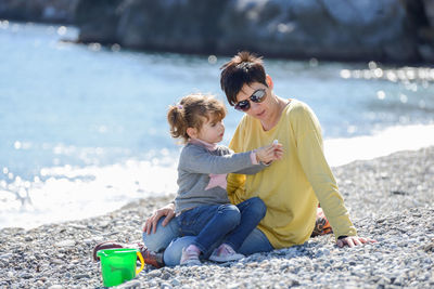 Full length of mother and daughter at beach