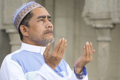 Close-up of man praying while standing at mosque