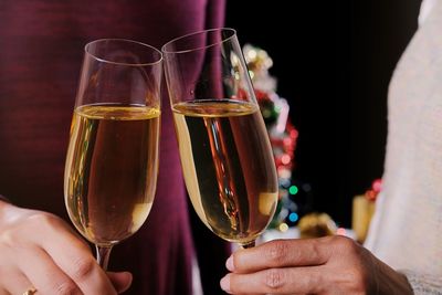 Midsection of couple toasting champions flutes during christmas 