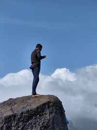 Man standing on rock against sky