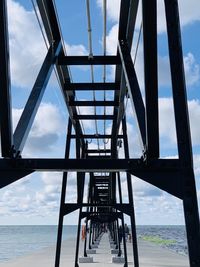Metallic structure by sea against sky