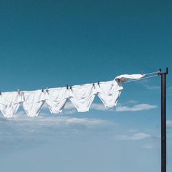 Low angle view of clothes drying on clothesline against blue sky