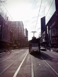 Road by street in city against sky