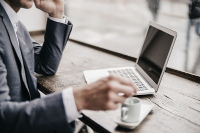 Midsection of man using mobile phone on table