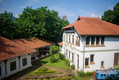 Houses by trees and buildings against sky