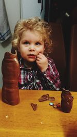 Close-up portrait of girl sitting on table at home